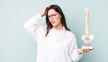 Genç, güzel bir kadın kafası karışmış, kafası karışmış, kaşınıyor. Omurga uzmanı konsepti