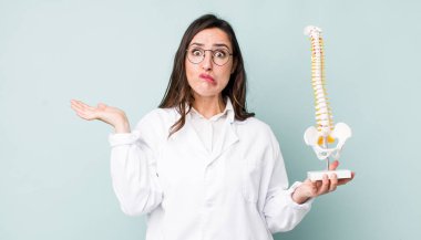 Genç ve güzel bir kadın şaşkın, şaşkın ve şüpheci hissediyor. Omurga uzmanı konsepti