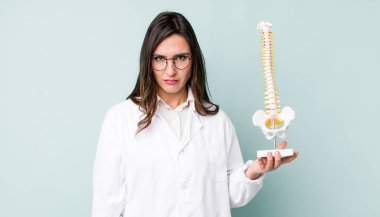 Genç, güzel bir kadın üzgün, üzgün ya da kızgın hissediyor ve yan tarafa bakıyor. Omurga uzmanı konsepti