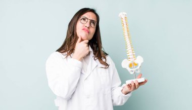 Genç, güzel bir kadın düşünüyor, kuşkulu ve şaşkın hissediyor. Omurga uzmanı konsepti