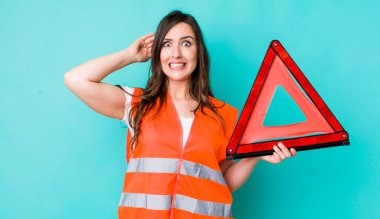 young pretty woman  feeling stressed, anxious or scared, with hands on head. car emergency triangle