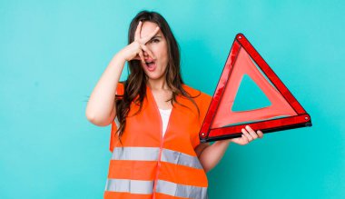 young pretty woman  looking shocked, scared or terrified, covering face with hand. car emergency triangle