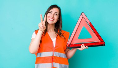 young pretty woman  smiling and looking friendly, showing number two. car emergency triangle