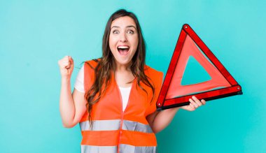 young pretty woman  shouting aggressively with an angry expression. car emergency triangle