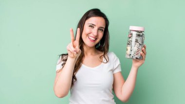 Genç, güzel bir bayan gülümsüyor ve iki numarayı gösteriyor. kaydetme kavramı