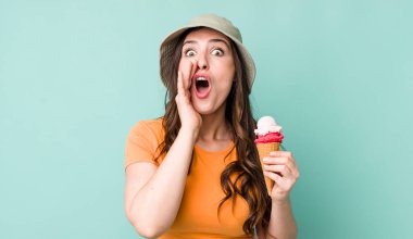 young pretty woman  feeling happy,giving a big shout out with hands next to mouth. summer and ice cream concept