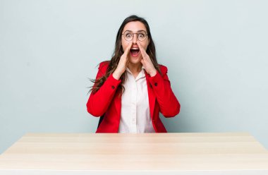 Genç, güzel bir kadın kendini mutlu hissediyor. Elleri ağzının kenarında bağırıyor. iş kavramı