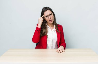 Genç ve güzel bir kadın kafası karışık ve şaşkın hissediyor, deli olduğunu gösteriyor. iş kavramı