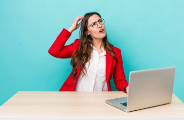 young pretty woman  smiling happily and daydreaming or doubting. business desk concept