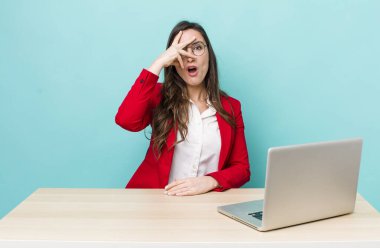 young pretty woman  looking shocked, scared or terrified, covering face with hand. business desk concept