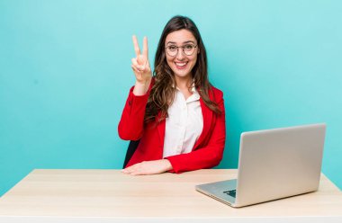 young pretty woman  smiling and looking friendly, showing number two. business desk concept
