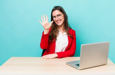 young pretty woman  smiling and looking friendly, showing number five. business desk concept