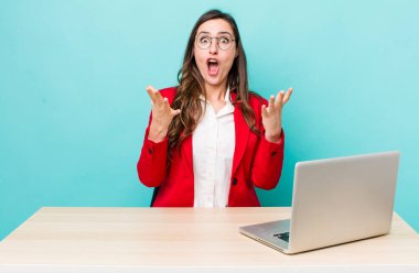 young pretty woman  feeling extremely shocked and surprised. business desk concept