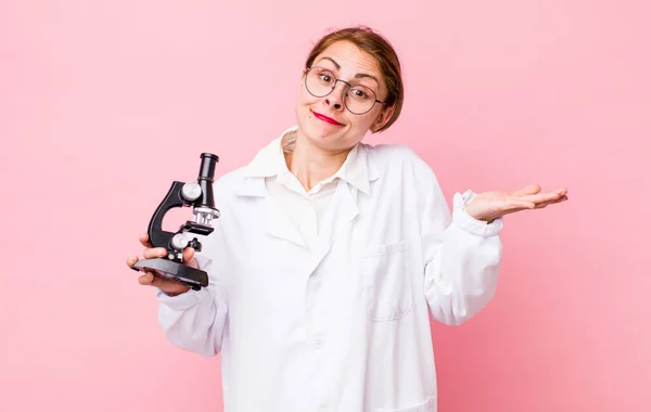 young pretty woman  feeling puzzled and confused and doubting. scientist with microscope concept