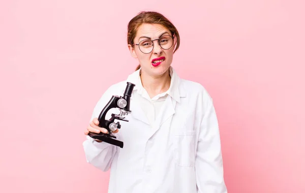 young pretty woman  looking puzzled and confused. scientist with microscope concept