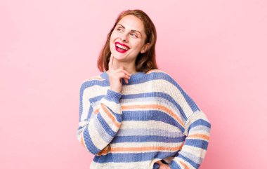 Genç ve güzel bir kadın mutlu bir şekilde gülümsüyor ve hayal kuruyor ya da şüphe ediyor.