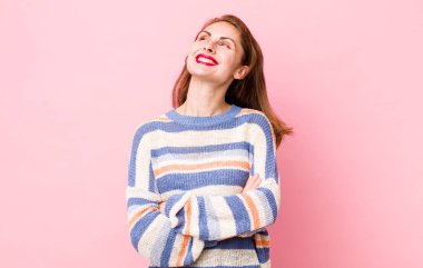 Genç, güzel bir kadın kendini mutlu, gururlu ve umutlu hissediyor, merak ediyor veya düşünüyor, çapraz kollarla boşluğu doldurmaya çalışıyor.