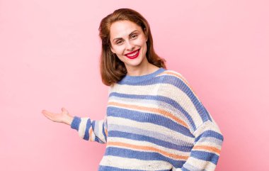 Genç ve güzel bir kadın mutlu ve neşeli hissediyor, gülümsüyor ve seni selamlıyor, dostça bir jestle içeri davet ediyor.