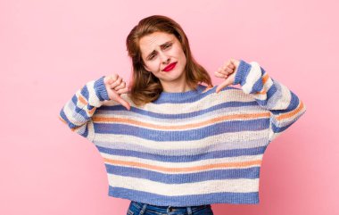 Genç, güzel bir kadın üzgün, hayal kırıklığına uğramış ya da kızgın görünüyor. Anlaşmazlıkta baş parmaklarını gösteriyor. Hayal kırıklığına uğramış hissediyor.