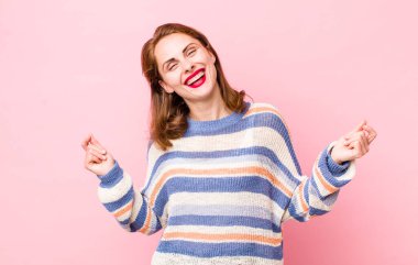 Genç, güzel bir kadın gülümsüyor, kaygısız hissediyor, rahat ve mutlu, dans ediyor ve müzik dinliyor, bir partide eğleniyor.