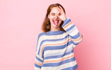 Genç ve güzel bir kadın mutlu bir şekilde gülümsüyor, şaka yapıyor ve gözetleme deliğinden bakıyor, sırları gözetliyor.