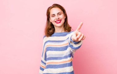 Genç ve güzel bir kadın gururla gülümsüyor ve gururla bir numaralı pozu veriyor, kendini lider gibi hissediyor.