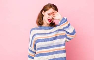 Genç ve güzel bir kadın stresli görünüyor, yorgun ve hayal kırıklığına uğramış, alnından ter damlıyor, umutsuz ve bitkin hissediyor.