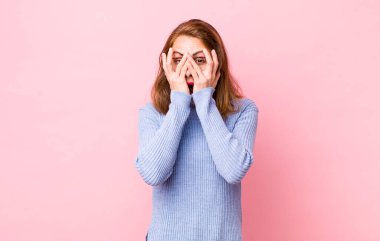 Genç, güzel bir kadın korkmuş ya da utanmış hissediyor. Gözleri yarı kapalı ya da ellerle dikizliyor.