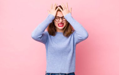 Genç ve güzel bir kadın stresli ve endişeli, depresif ve hayal kırıklığına uğramış hissediyor, iki elini de başa kaldırıyor.