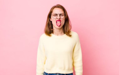 Genç ve güzel bir kadın, tiksinmiş ve rahatsız olmuş hissediyor. Dilini dışarı çıkarıyor, iğrenç ve iğrenç bir şeyden hoşlanmıyor.