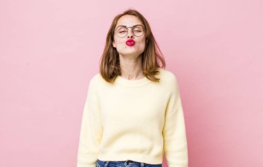 Genç, güzel bir kadın dudaklarını birbirine bastırıyor. Sevimli, eğlenceli, mutlu, sevimli bir yüz ifadesiyle. Öpücük yolluyor.