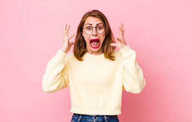 Genç ve güzel bir kadın ellerini havaya kaldırarak bağırıyor. Öfkeli, sinirli, stresli ve üzgün.