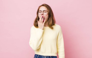 Genç ve güzel bir kadın sabahın erken saatlerinde uykulu, yorgun ve sıkkın bir şekilde esniyor.