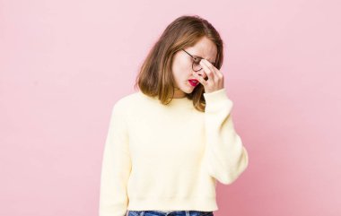 Genç ve güzel bir kadın stresli, mutsuz ve hayal kırıklığına uğramış, alnına dokunuyor ve şiddetli baş ağrısı çekiyor.