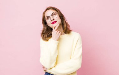 Genç, güzel bir kadın düşünceli, meraklı ya da hayal kuruyor, hayal kuruyor ve gökyüzüne bakıyor.