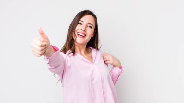 Genç, güzel bir kadın gururlu, tasasız, kendinden emin ve mutlu, başparmağıyla olumlu gülümsüyor.