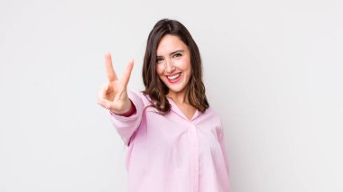 Genç, güzel bir kadın gülümsüyor ve arkadaş canlısı görünüyor. İki ya da iki numarayı gösteriyor. Elleri önde, geri sayıyor.