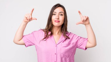 Genç, güzel bir kadın iki eliyle kendi gülüşünü çiziyor, olumlu ve mutlu görünüyor, sağIık kavramı.