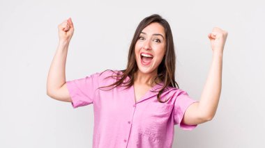 Genç ve güzel bir kadın muzaffer bir şekilde bağırıyor. Heyecanlı, mutlu ve şaşırmış görünüyor. Kutlama yapıyor.