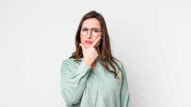 Genç ve güzel bir kadın ciddi, düşünceli ve güvensiz görünüyor. Bir kolu çapraz, eli çenesinde, seçenekleri değerlendiriyor.