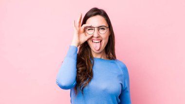 Genç ve güzel bir kadın mutlu bir şekilde gülümsüyor, şaka yapıyor ve gözetleme deliğinden bakıyor, sırları gözetliyor.