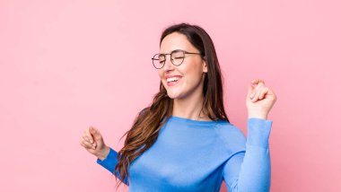 Genç, güzel bir kadın gülümsüyor, kaygısız hissediyor, rahat ve mutlu, dans ediyor ve müzik dinliyor, bir partide eğleniyor.