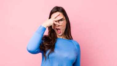 Genç, güzel bir kadın şok olmuş, korkmuş ya da korkmuş görünüyor. Yüzü elle kaplanmış ve parmaklarının arasından gizlice bakıyor.