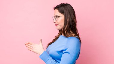 Genç, güzel bir kadın gülümsüyor, sizi selamlıyor ve başarılı bir anlaşma için el sıkışmayı teklif ediyor, işbirliği konsepti.