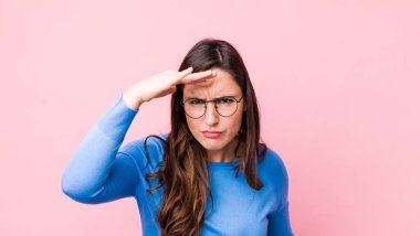 Genç, güzel bir kadın şaşkınlık ve şaşkınlık içinde bakıyor. Alnı açık, uzaklara bakıyor, izliyor ya da arıyor.