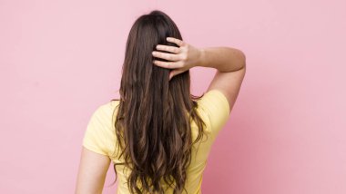 Genç, güzel bir kadın düşünüyor ya da şüphe ediyor, kafasını kaşıyor, kafası karışık ve kafası karışık hissediyor, geriye ya da arkaya bakıyor.