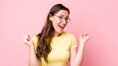 Genç ve güzel bir kadın son derece mutlu ve şaşırmış görünüyor, başarıyı kutluyor, bağırıyor ve zıplıyor.