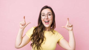 Genç, güzel bir kadın iki eliyle kendi gülüşünü çiziyor, olumlu ve mutlu görünüyor, sağIık kavramı.