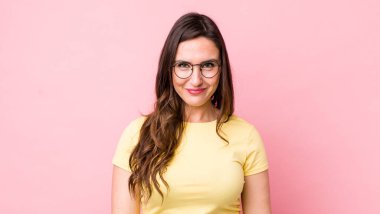 Genç ve güzel bir kadın pozitif ve kendinden emin gülümsüyor. Tatmin olmuş, arkadaş canlısı ve mutlu görünüyor.