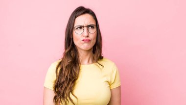 Genç ve güzel bir kadın kafası karışmış görünüyor, merak ediyor veya bir sorunu çözmeye çalışıyor ya da düşünüyor.